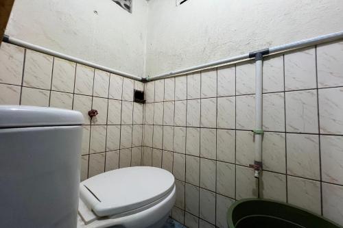 a bathroom with a toilet and a tiled wall at OYO 93429 Pondok Surya in Pakato