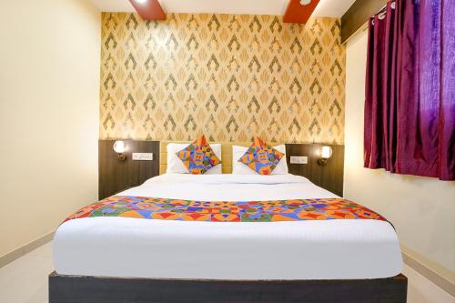 KolshetにあるFabHotel Sai Viharのベッドルーム(カラフルなシーツを使用した大きな白いベッド付)