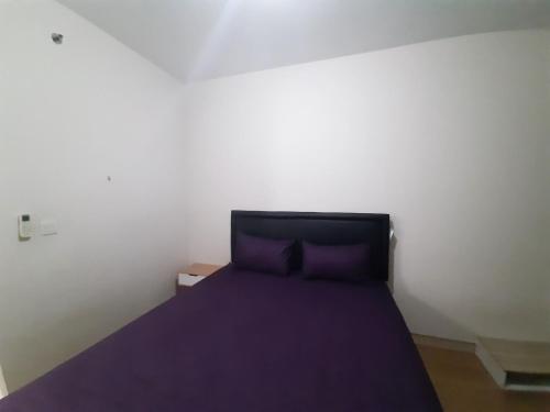 a bedroom with a bed with a purple bedspread at The Springlake Summarecon by Bonzela Property in Kandang Satu
