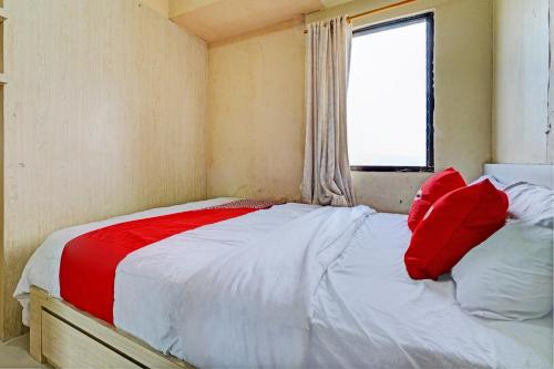 Una cama con almohadas rojas en una habitación pequeña. en OYO 93456 Apartemen Gateway Cicadas By Inpro Ii en Bandung