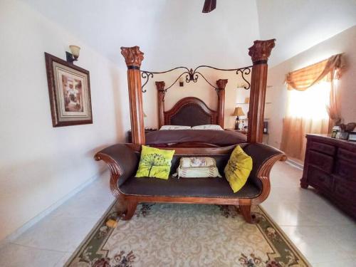 a bedroom with a large wooden bed with yellow pillows at La Romana Vacation Home in Cumayasa Kilómetros 4 1/2
