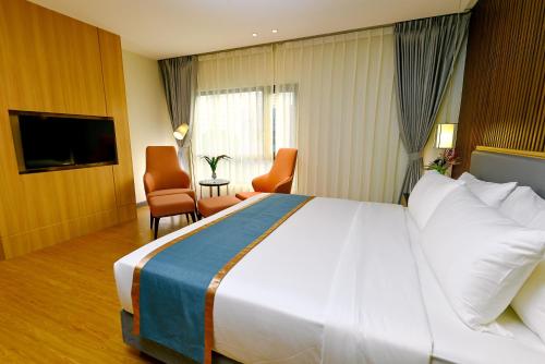 a hotel room with a large bed and a television at Ardenhills Suites in Manila