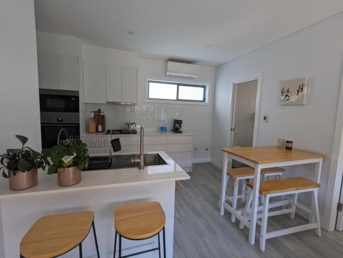 2 bedroom apartment with Garden views in Sydney في سيدني: مطبخ مع حوض وطاولة مع كراسي