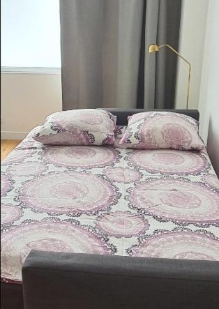 - un lit dans une chambre avec des oreillers roses et blancs dans l'établissement Chez vous au coeur de Paris Convention - Vaugirard, à Paris