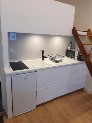 une cuisine blanche avec un évier et un micro-ondes dans l'établissement Chez vous au coeur de Paris Convention - Vaugirard, à Paris