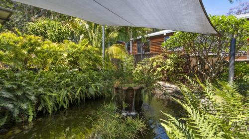 an umbrella over a pond in a garden at Beachside Oasis Pearl Beach in Pearl Beach