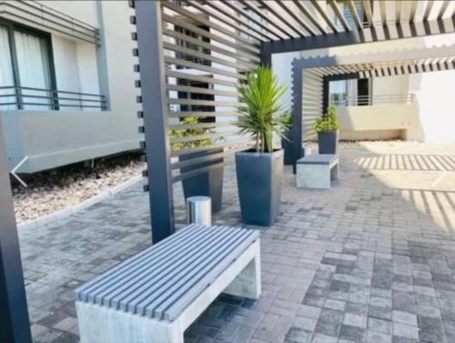 a patio with a bench and potted plants at City junction studio apartment in Windhoek