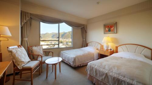 a hotel room with two beds and a window at Kamogawakan in Kamogawa