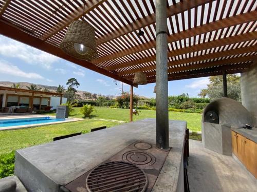 una cocina al aire libre con horno de pizza bajo un techo de madera en Casa de campo con piscina, en Miraflores