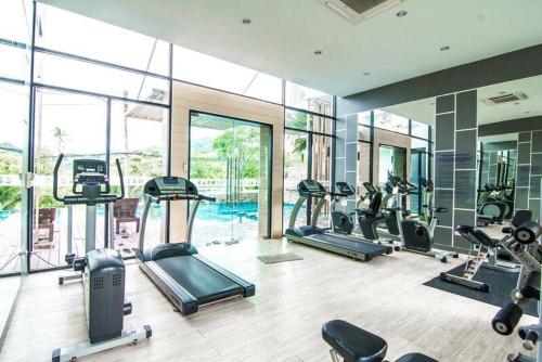 a gym with treadmills and ellipticals in a room with windows at Risa Plus2 in Kathu