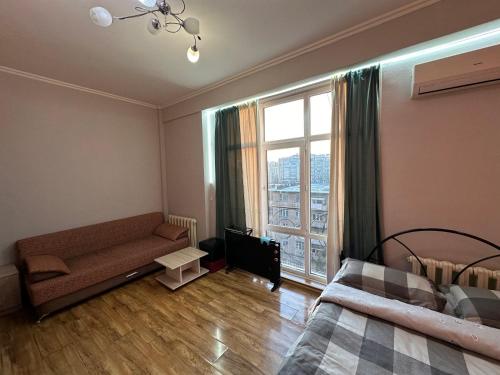 een woonkamer met een bank en een groot raam bij 1-room apart. 21 on Usenbaeva 52 near Eurasia shopping center in Bisjkek