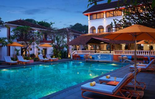 a swimming pool with chairs and umbrellas in front of a building at Hyatt Ronil Goa - a JdV by Hyatt Hotel in Calangute