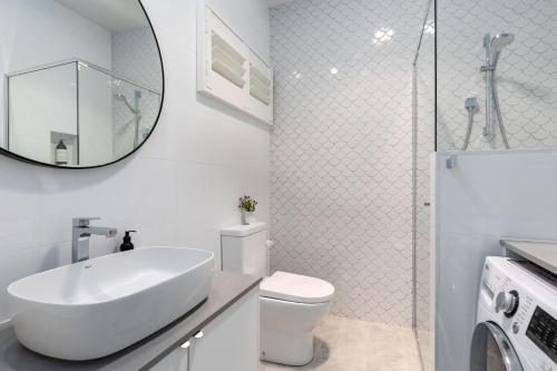 bagno con lavandino, servizi igienici e specchio di Studio By The Bay a Vincentia