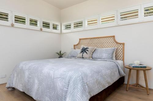 una camera da letto con un letto con pareti e finestre bianche di Studio By The Bay a Vincentia