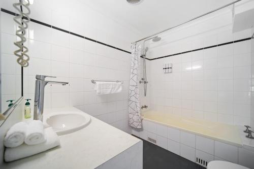 Golf Place Inn Wollongong في Primbee: حمام أبيض مع حوض وحوض استحمام