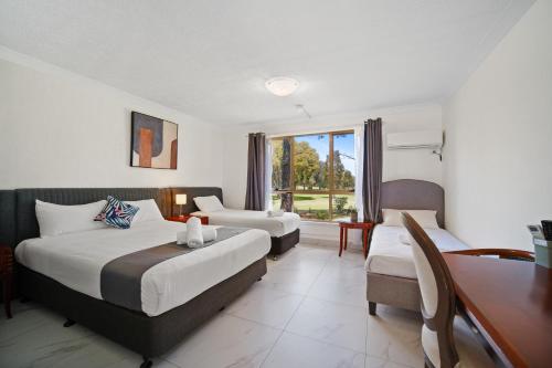 a hotel room with two beds and a desk at Golf Place Inn Wollongong in Wollongong