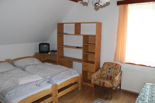 a bedroom with a bed and a book shelf and a chair at Penzion Mühl in Bedřichov