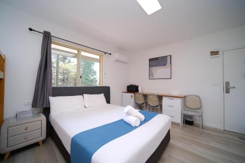 a bedroom with a bed and a desk and a window at Golf Place Inn Wollongong in Wollongong