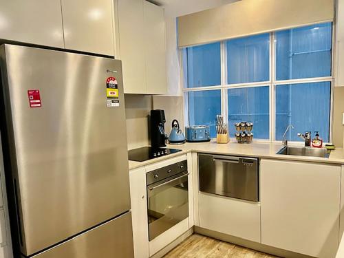 a kitchen with a stainless steel refrigerator and a sink at Heart of Sydney CBD Chic One Bedroom Apartment with Pool on Bridge Street in Sydney