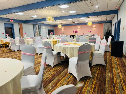 a banquet hall with white tables and white chairs at Albany Airport Inn in Albany