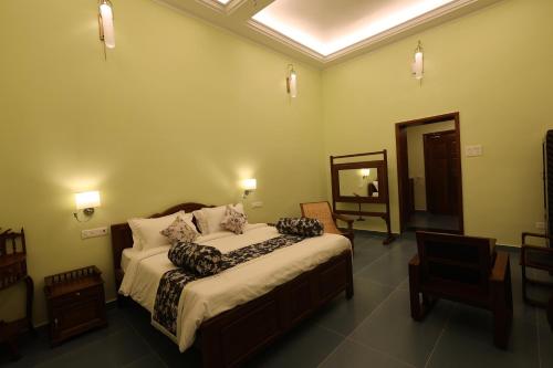 a bedroom with a bed and a chair and a mirror at Le Colonial Suites in Puducherry