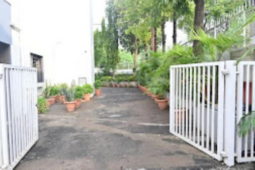 a driveway with a white fence and potted plants at HOTEL PRITAM PARK, Jalgaon, Maharashtra in Jālgaon