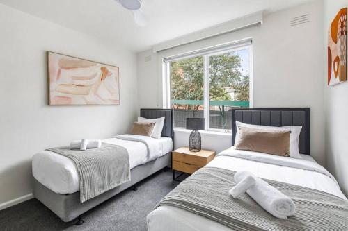 - une chambre avec 2 lits et une fenêtre dans l'établissement Urban Green - Stylish Courtyard Haven off Malvern Rd, à Melbourne