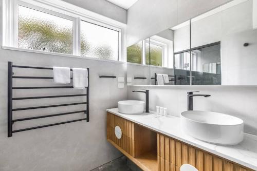 La salle de bains est pourvue de 2 lavabos et d'un grand miroir. dans l'établissement Urban Green - Stylish Courtyard Haven off Malvern Rd, à Melbourne