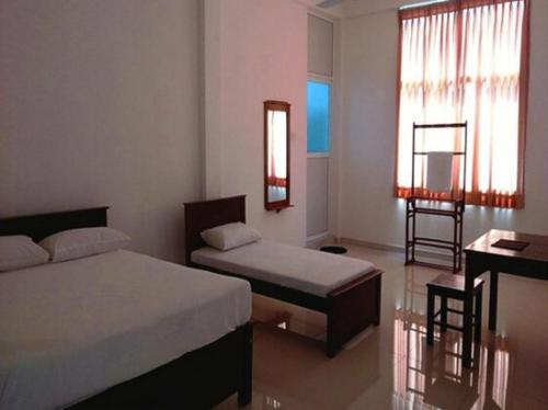 1 dormitorio con 2 camas, escritorio y ventana en Vintop Hotel & Homestays Gampaha, en Gampaha