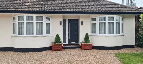a white house with two windows and two plants at The Golf Studio Woodhall Spa in Woodhall Spa