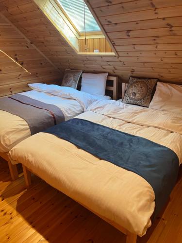 Habitación con suelo de madera y 2 camas. en 山中湖湖畔高級ログハウス 充電富士168 en Yamanakako