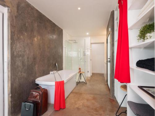 een badkamer met een wit bad en rode gordijnen bij Milner Fashion House in Pretoria