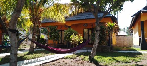 a hammock in front of a house with palm trees at Pandan Bungalow in Gili Air