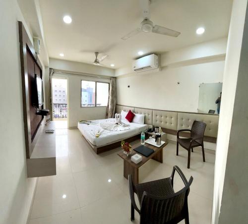 a hotel room with a bed and a table and chairs at Hotel Sai Chhatra in Shirdi