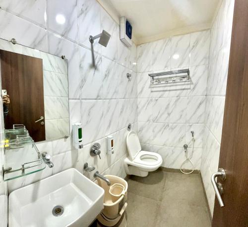 a white bathroom with a sink and a toilet at Hotel Sai Chhatra in Shirdi