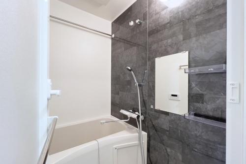 a bathroom with a tub and a shower with a mirror at KISETSU Waseda I in Tokyo