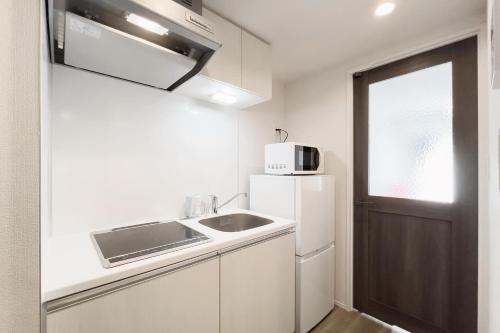 a white kitchen with a sink and a microwave at KISETSU Waseda I in Tokyo
