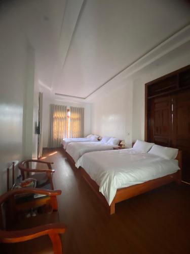 a bedroom with two beds and a chair at Cao Son Hotel in Bắc Quang