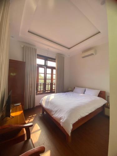 a bedroom with a large white bed and a window at Cao Son Hotel in Bắc Quang