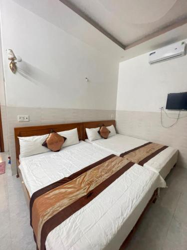 a bedroom with two beds with white sheets and brown pillows at Hưng Phát Hotel in Phu Yen