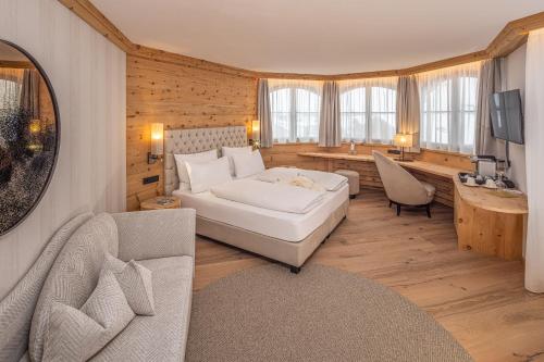 1 dormitorio con cama, sofá y escritorio en Savoy Dolomites Luxury & Spa Hotel en Selva di Val Gardena