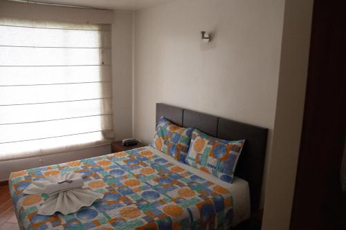 a bedroom with a bed with a comforter and a window at Hotel El Castillo Chinauta in Chinauta