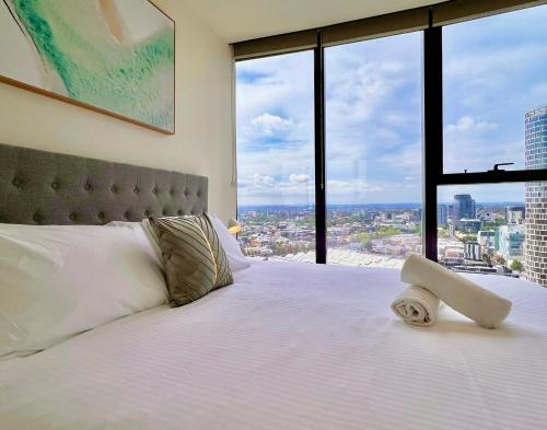 a bedroom with a white bed with a large window at Highrise Best Location 2 Bedrooms & 2 Bathrooms in Melbourne