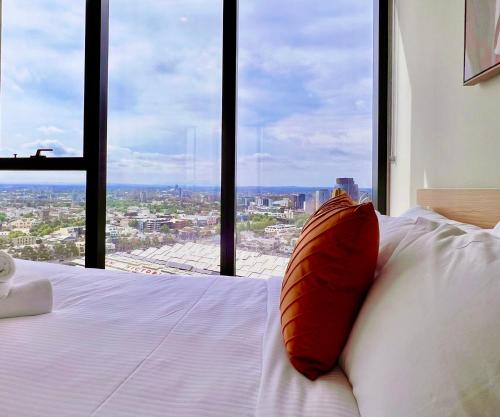 a bed with a red pillow in front of a window at Highrise Best Location 2 Bedrooms & 2 Bathrooms in Melbourne