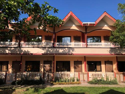 an apartment building with a white fence and a tree at JBR Tourist Inn - Port Barton in Itaytay