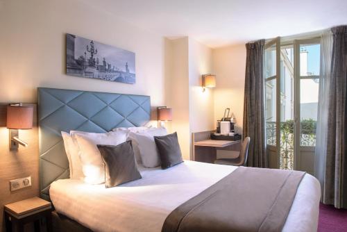 パリにあるホテル アストンの大きなベッドと窓が備わるホテルルームです。