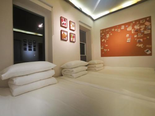 um quarto com uma pilha de almofadas brancas e uma janela em 此时此刻民宿This Moment B&B em Miyun