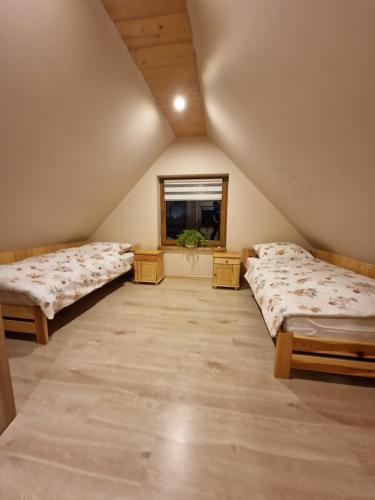 a attic room with two beds and a window at Domek Aniula in Istebna