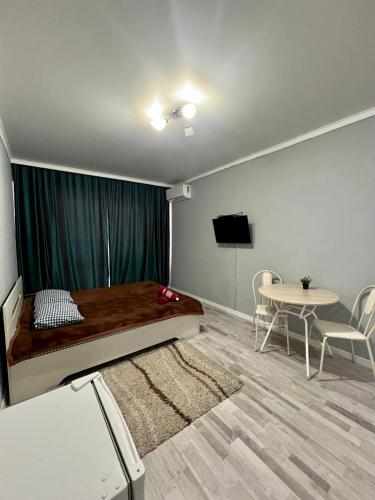 アルマトイにあるУютная квартира недалеко от аэропортаのベッドルーム(ベッド1台、テーブル、テレビ付)