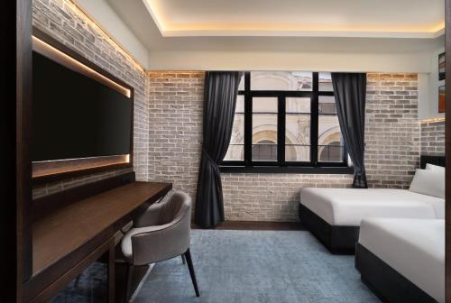 a bedroom with a bed and a desk and a tv at DeCamondo Galata, a Tribute Portfolio Hotel in Istanbul